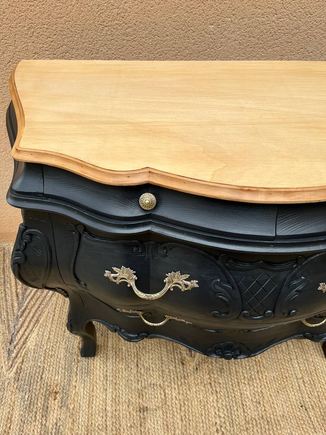 Curved commode painted in black and wood.