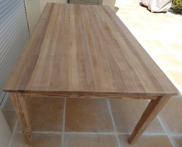 Large natural wood table with rectangular top supported by legs