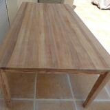 Large natural wood table with rectangular top supported by legs