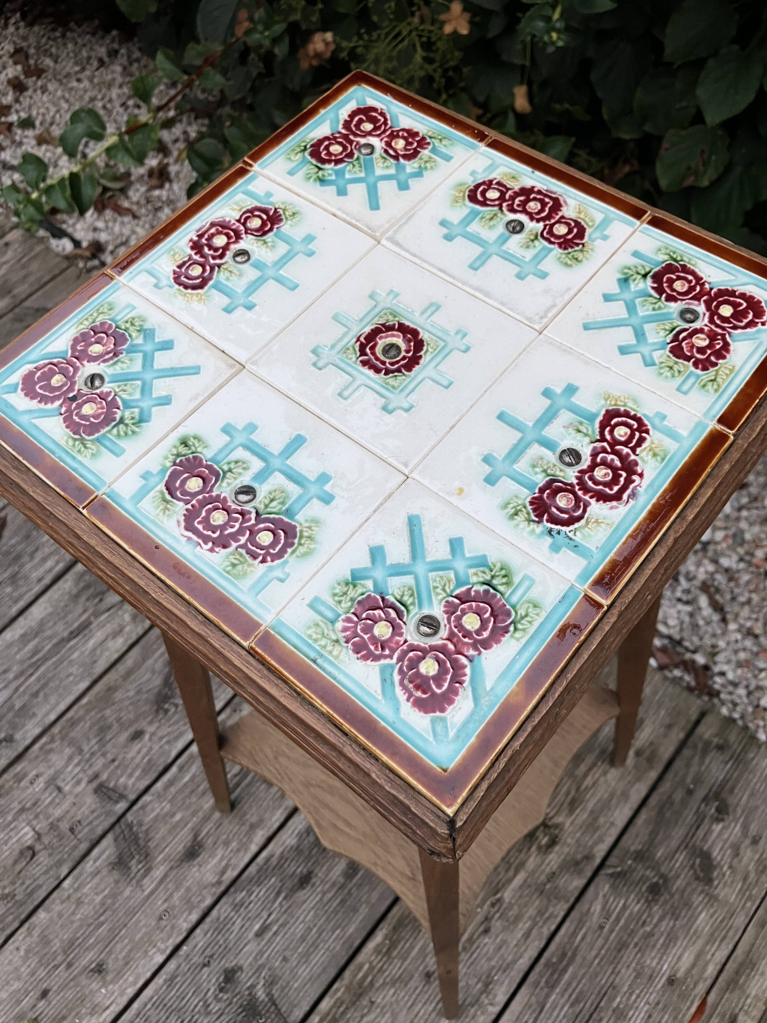 Antique wooden plant stand with ceramic tiles.
