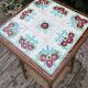 Antique wooden plant stand with ceramic tiles.