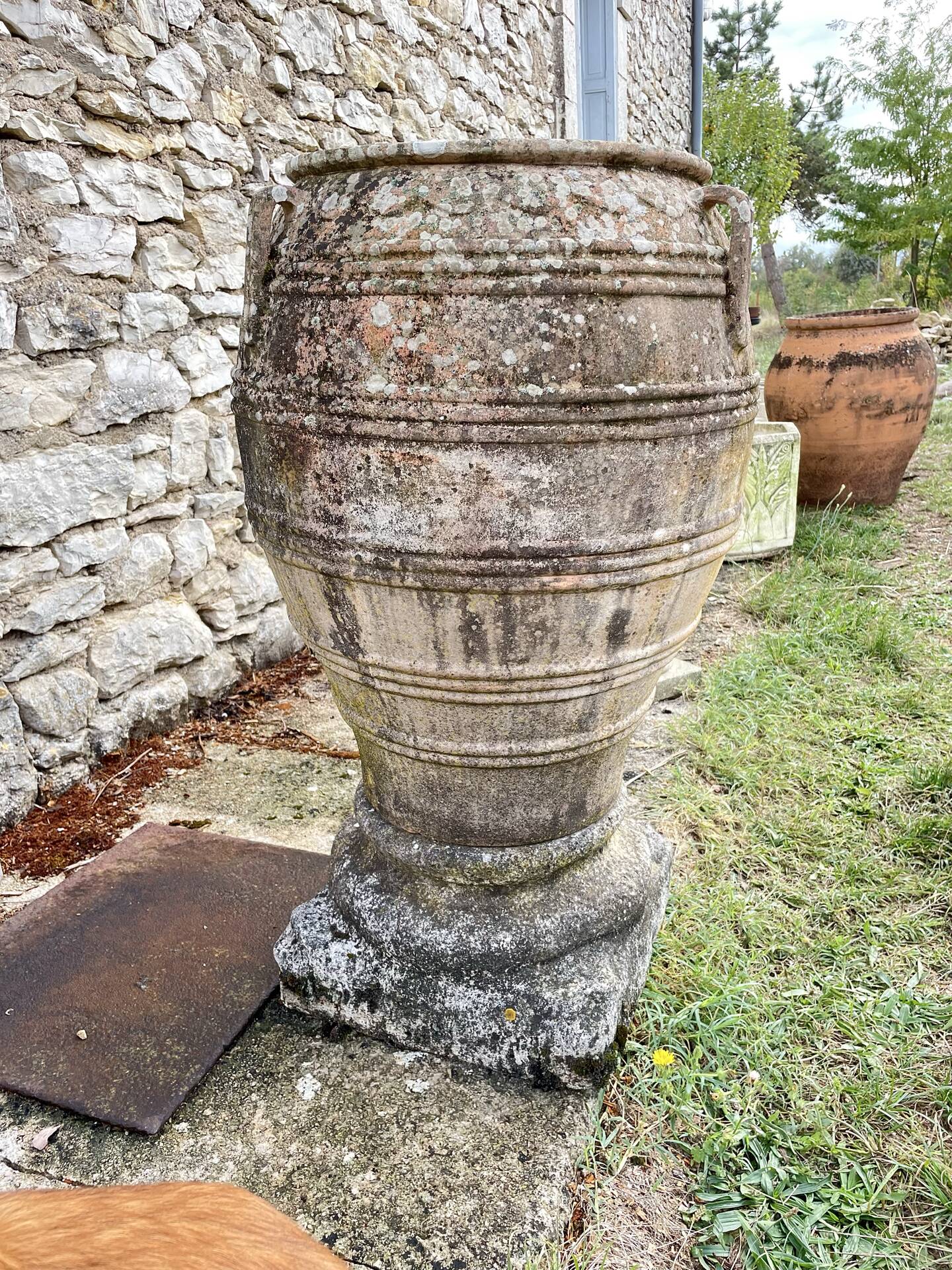 Large Cretan jar in terracotta with three handles on a stone base.