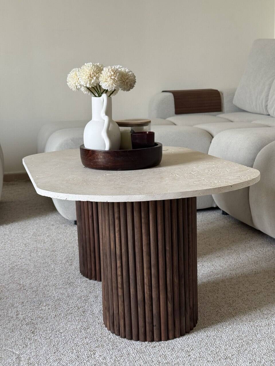 Oval coffee table in travertine and fluted wood.