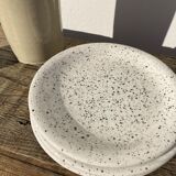 4 black speckled dessert plates on a vintage white background
