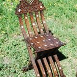 A folding chair and a carved Syrian table with 19th-century mother-of-pearl inlays.