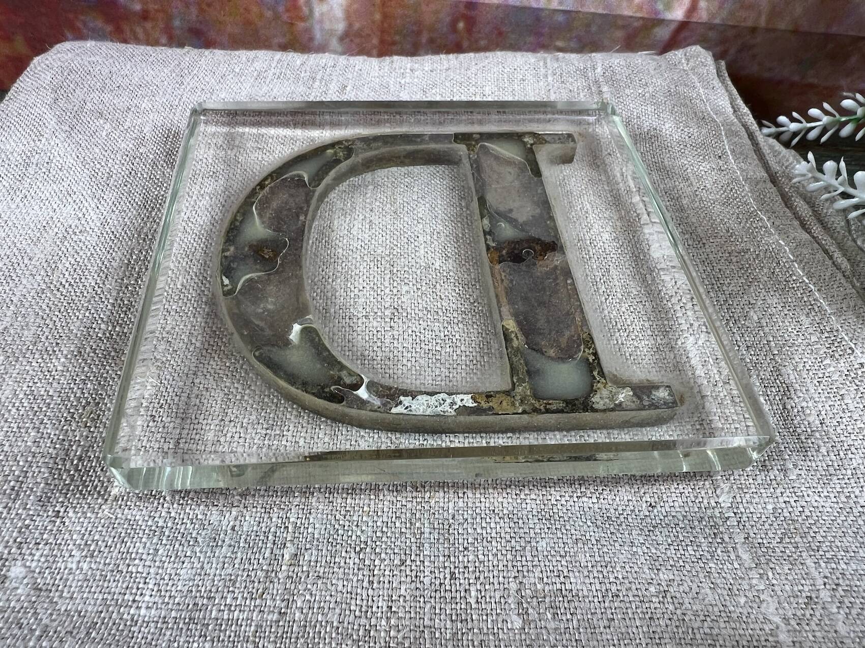 Metal letter D on glass plate