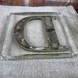 Metal letter D on glass plate