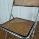 Vintage folding chair in metal and cane.