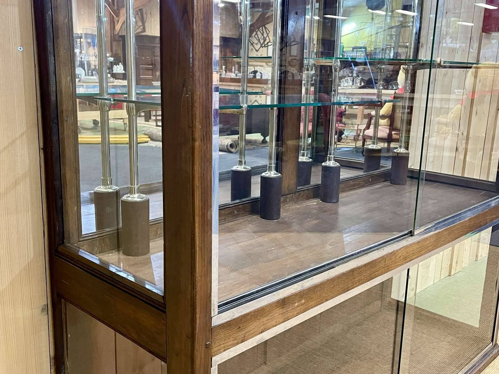 Early 20th-century shop display cabinet in oak with sliding doors.