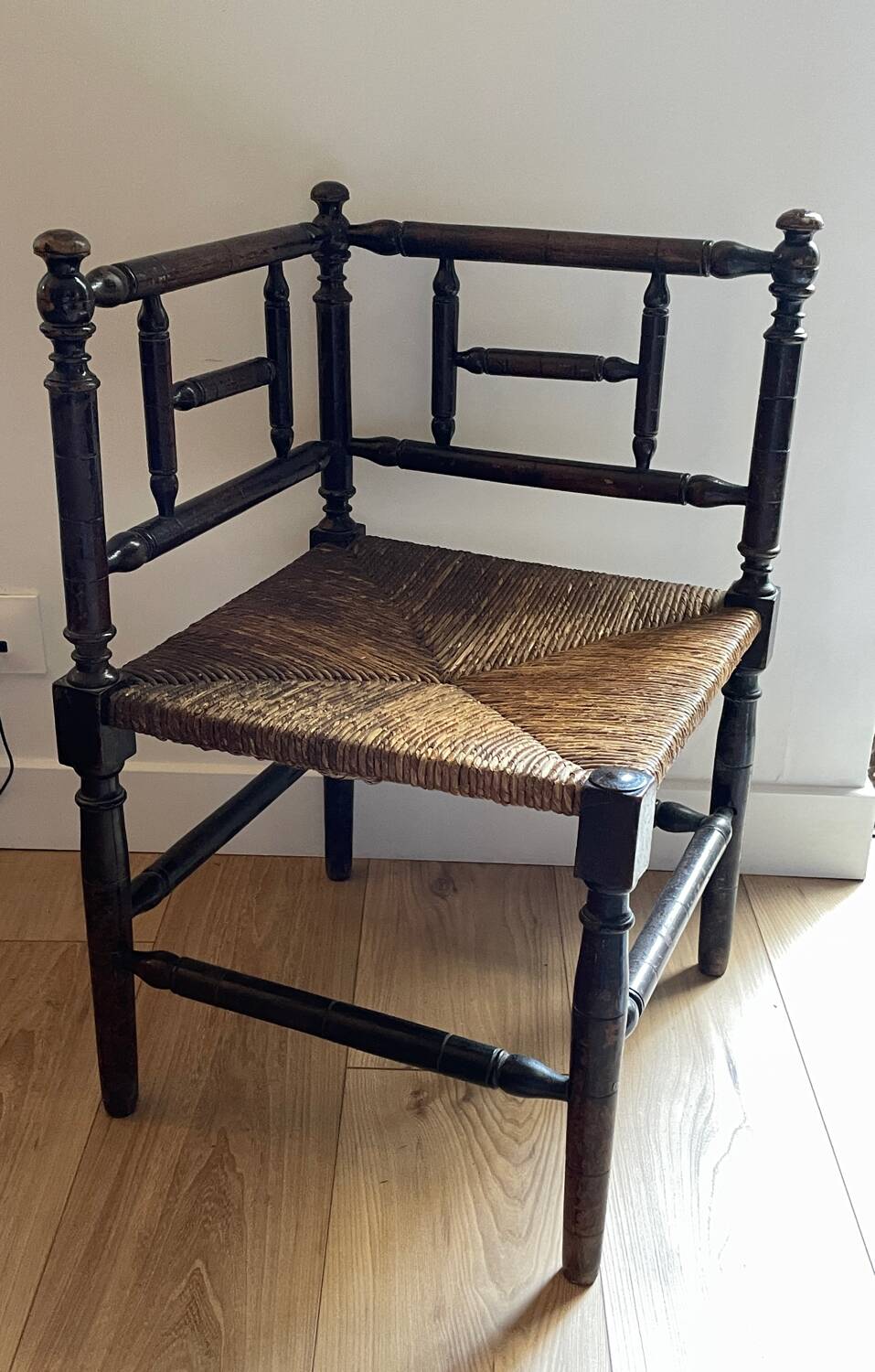 Corner chair made of turned wood with a straw seat.