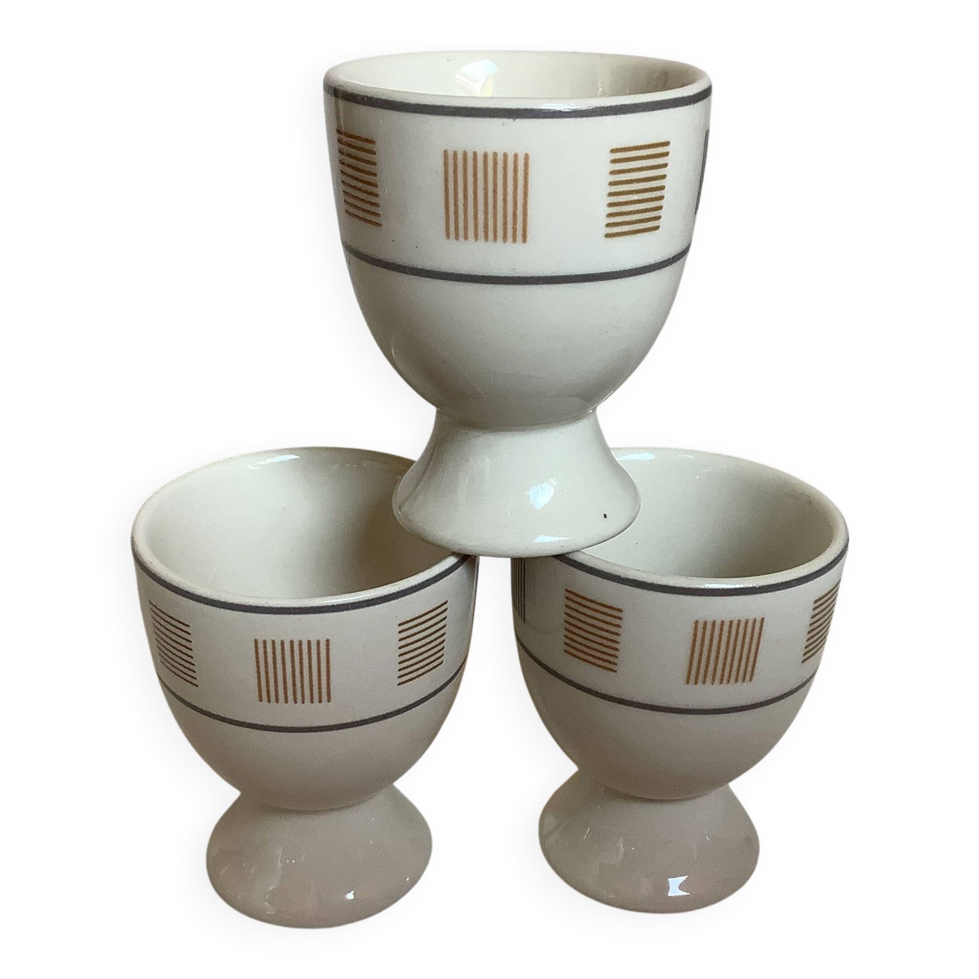 Three egg cups with geometric patterns in beige and brown.