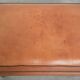 Handy sheepskin ottoman with warm colours finished with black piping