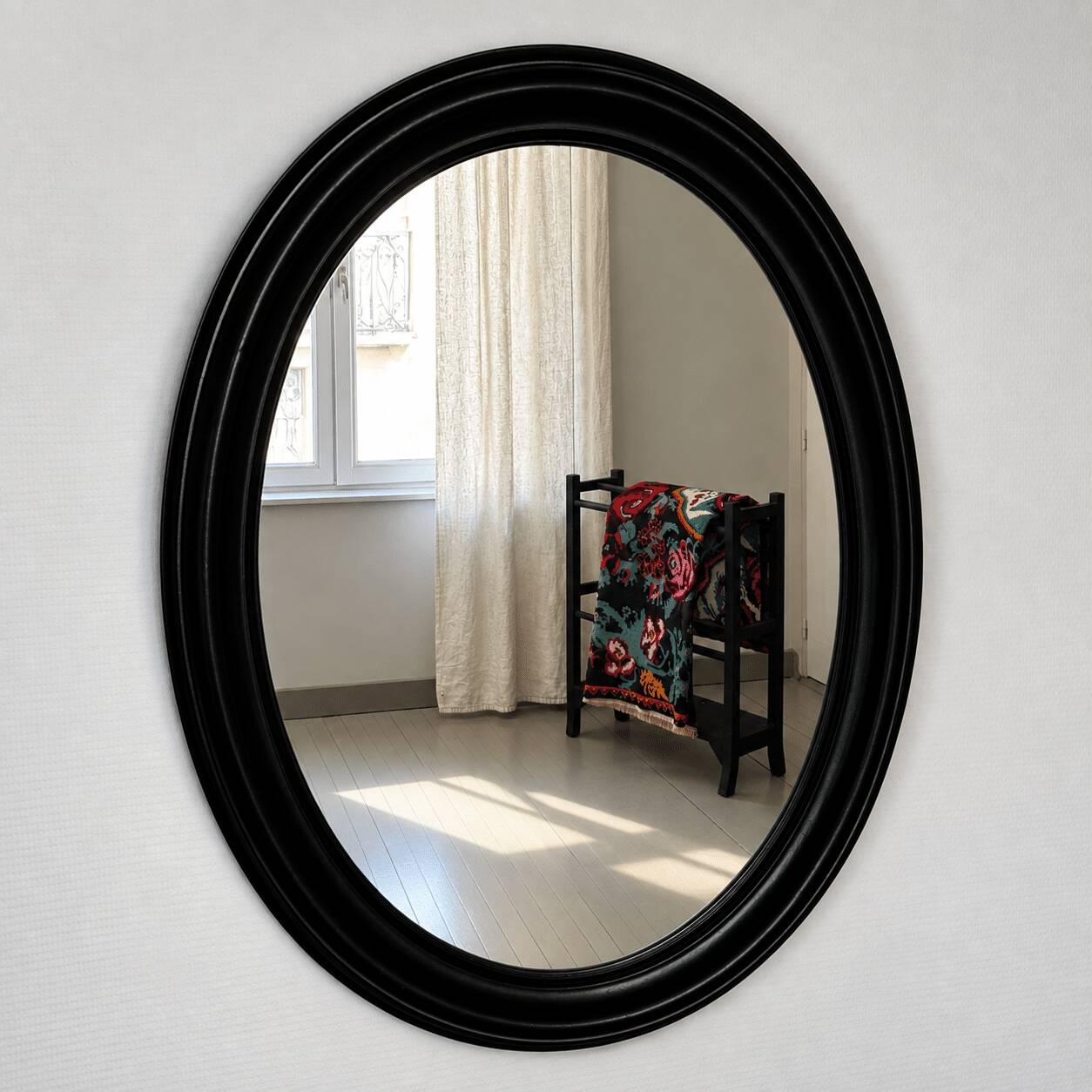 Antique oval mirror in patinated black wood