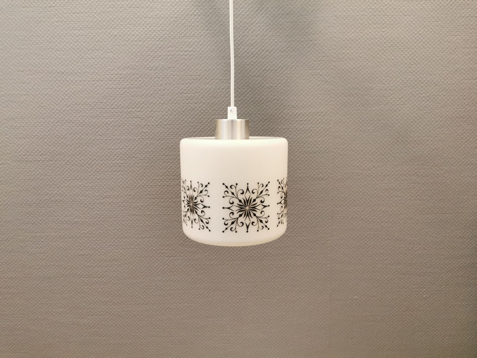 Scandinavian hanging lamp in white glass with inlayed black motifs.