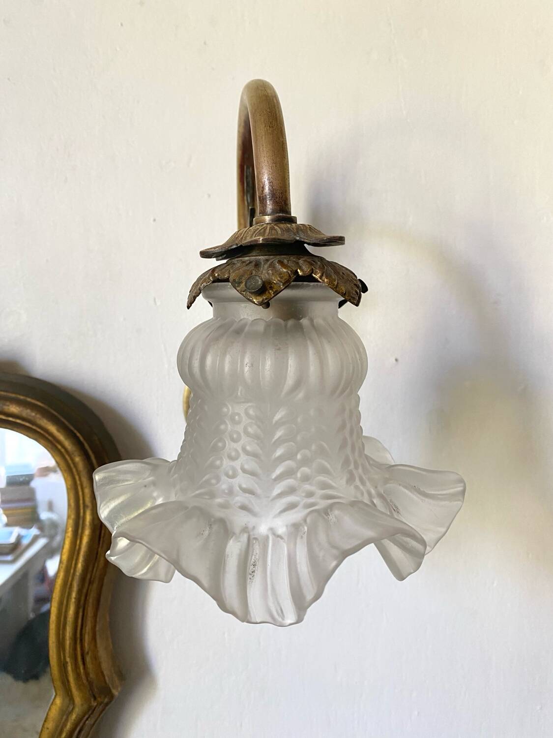 Antique brass wall light with glass shade.