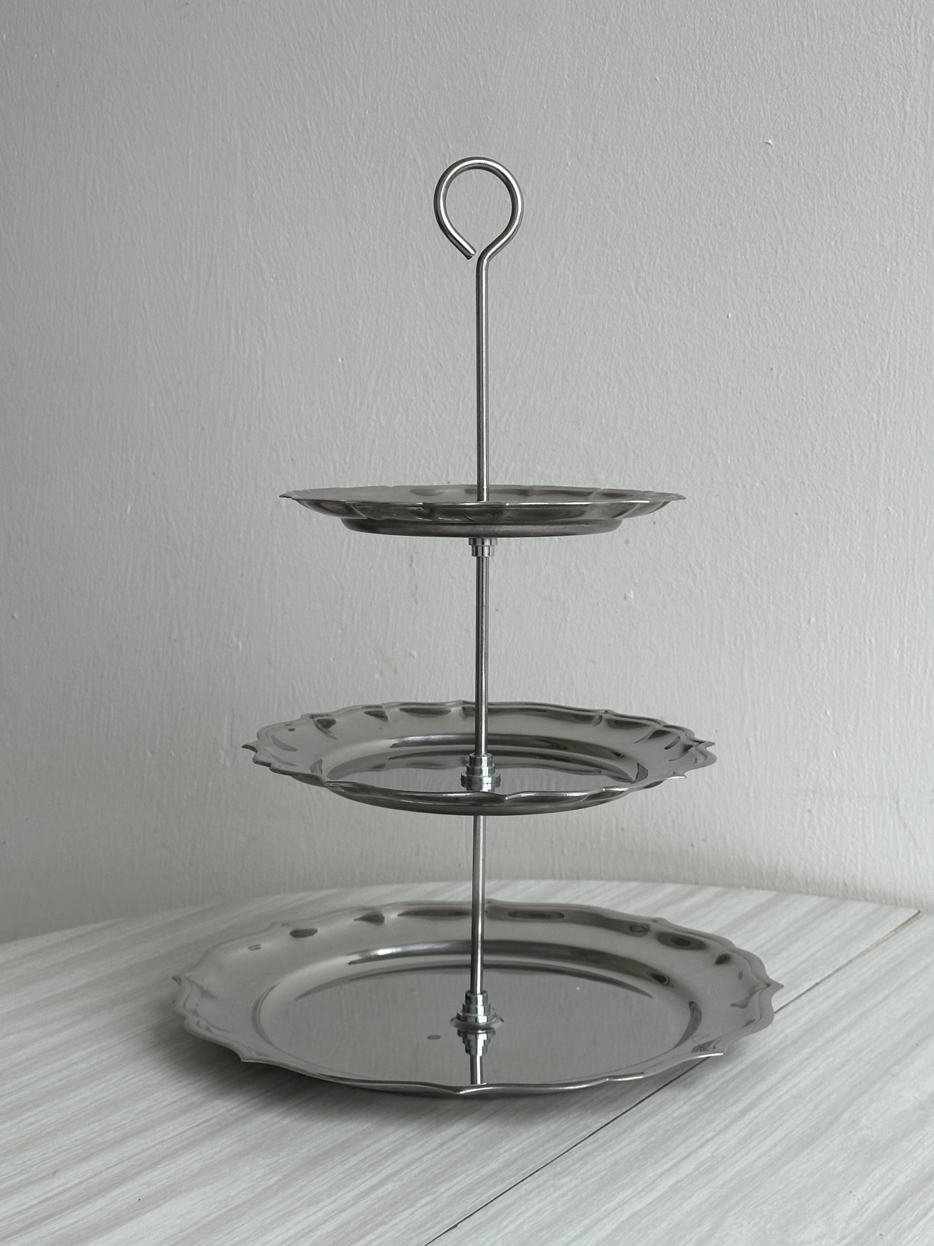 Three-tiered serving trolley in shiny stainless steel.