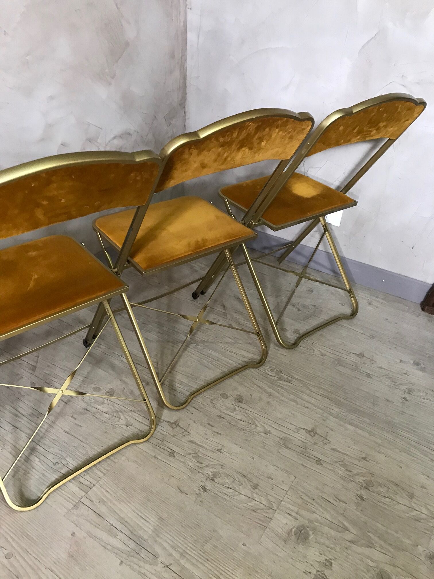 Four folding velvet and brass chairs