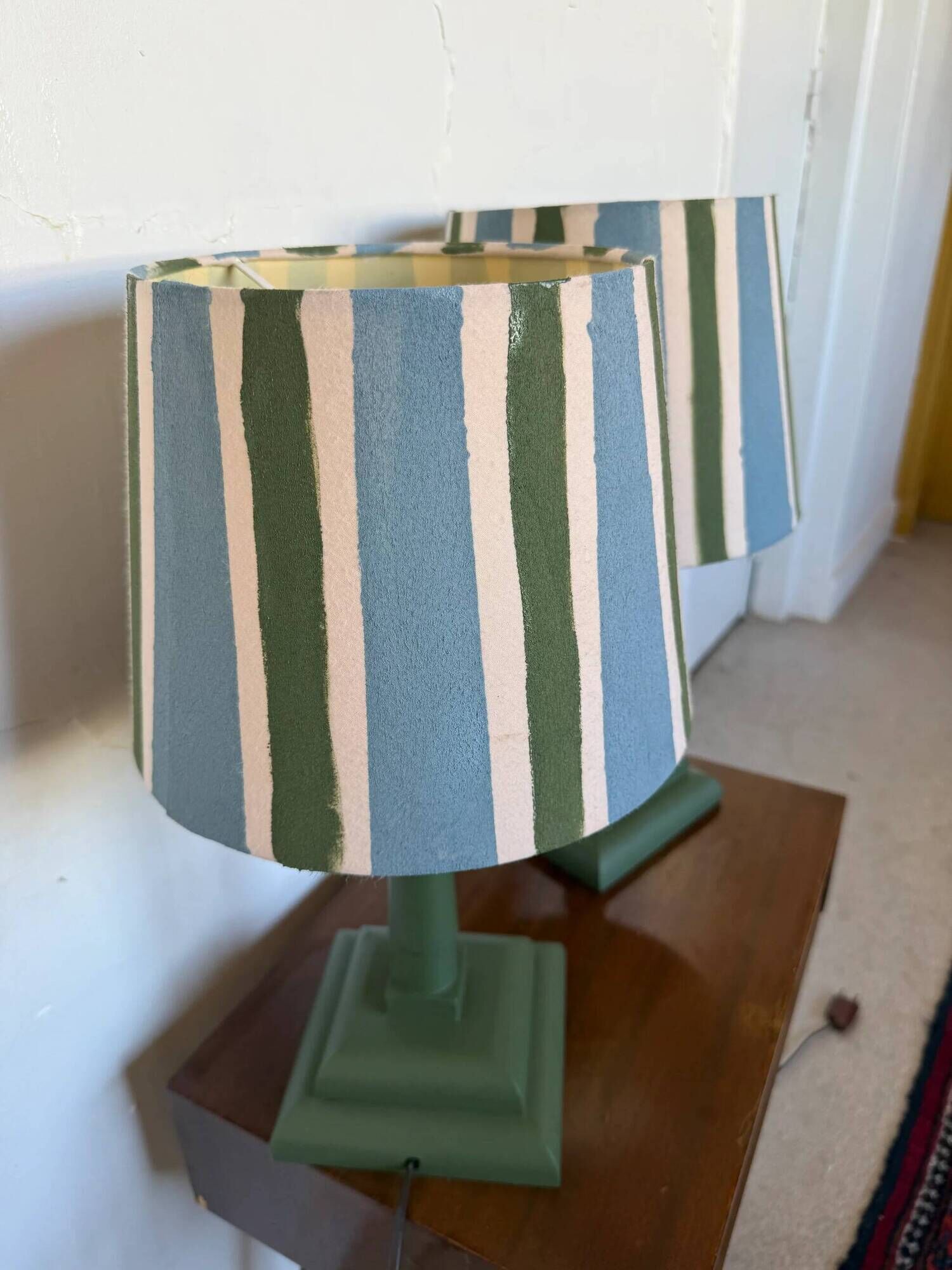 Pair of vintage wooden lamps with their striped beige, blue, and green shades.
