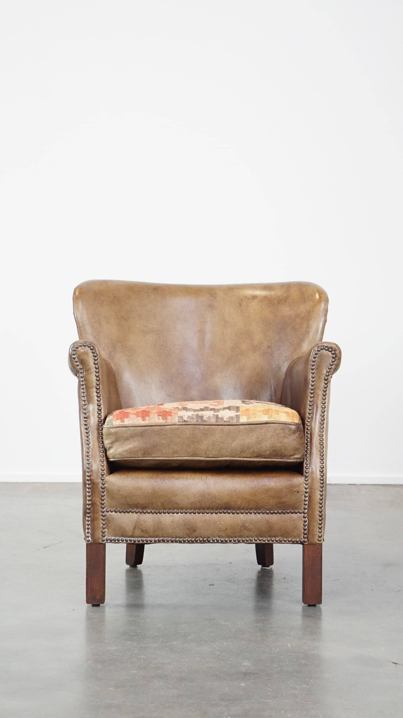 Subtle leather armchair with a reversible kilim seat cushion