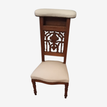 Prie-god furniture in the shape of a low seat with an armnedle on which one kneels to pray
