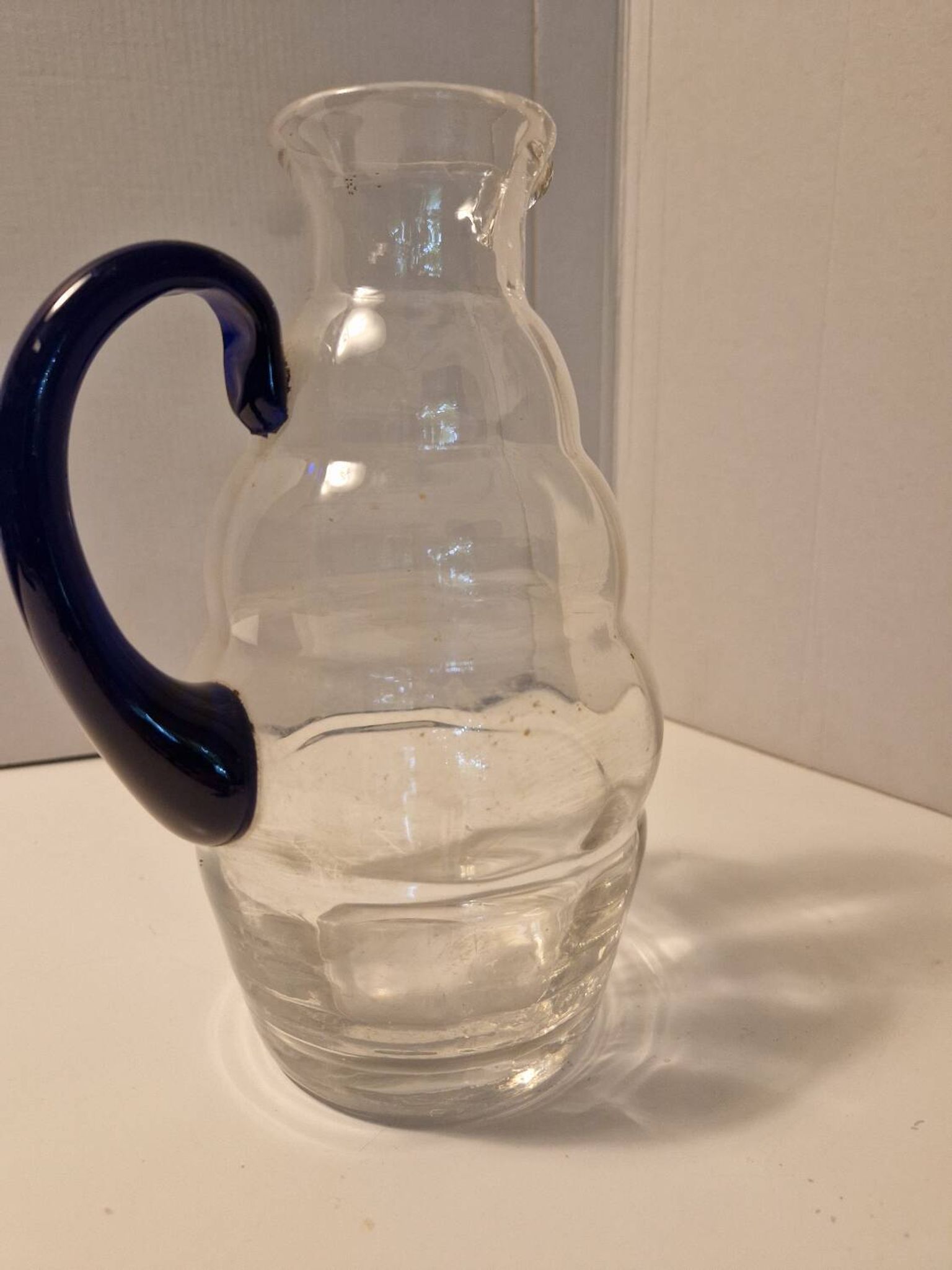 Glass carafe with wavy body and blue handle