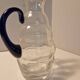 Glass carafe with wavy body and blue handle