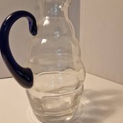 Glass carafe with wavy body and blue handle