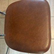 Two brown faux leather chairs.