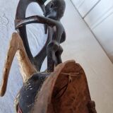 A large Senufo mask made of colored wood, decorated with an anthropomorphic figure