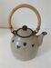 Beige stoneware teapot with stylized flowers and rattan handle