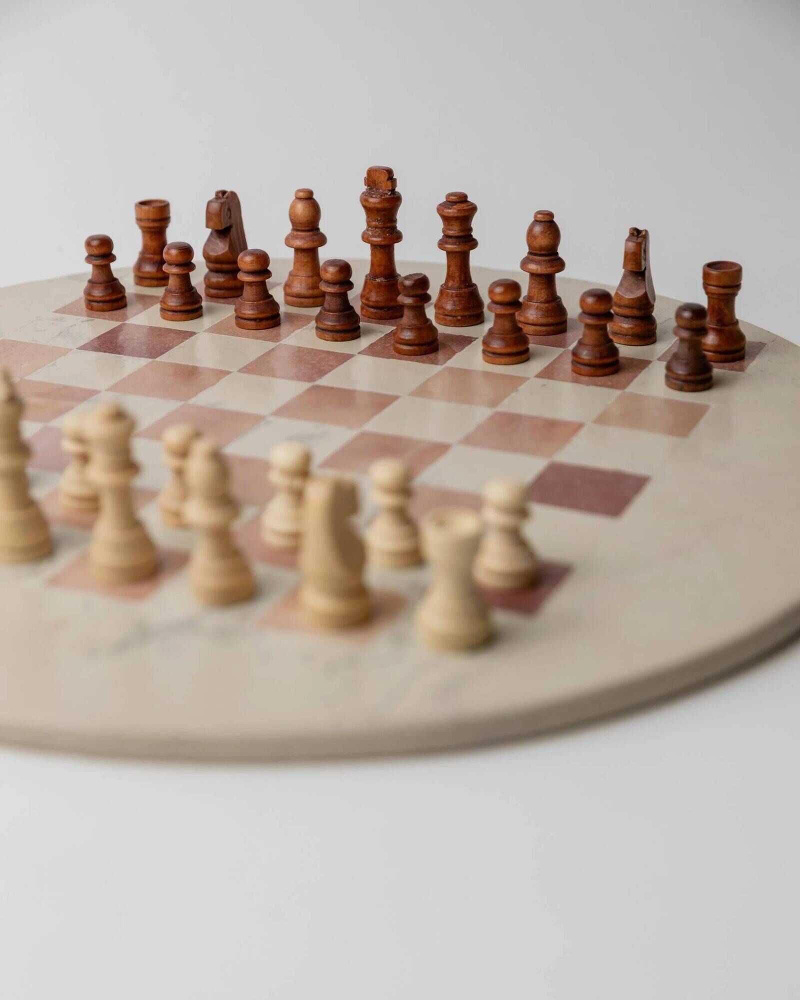 Vintage 1980s round chess set in marble, with a beige and pink marble board and wooden pieces.