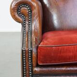 Sheep leather wingback chair with a red corduroy seat cushion and patina