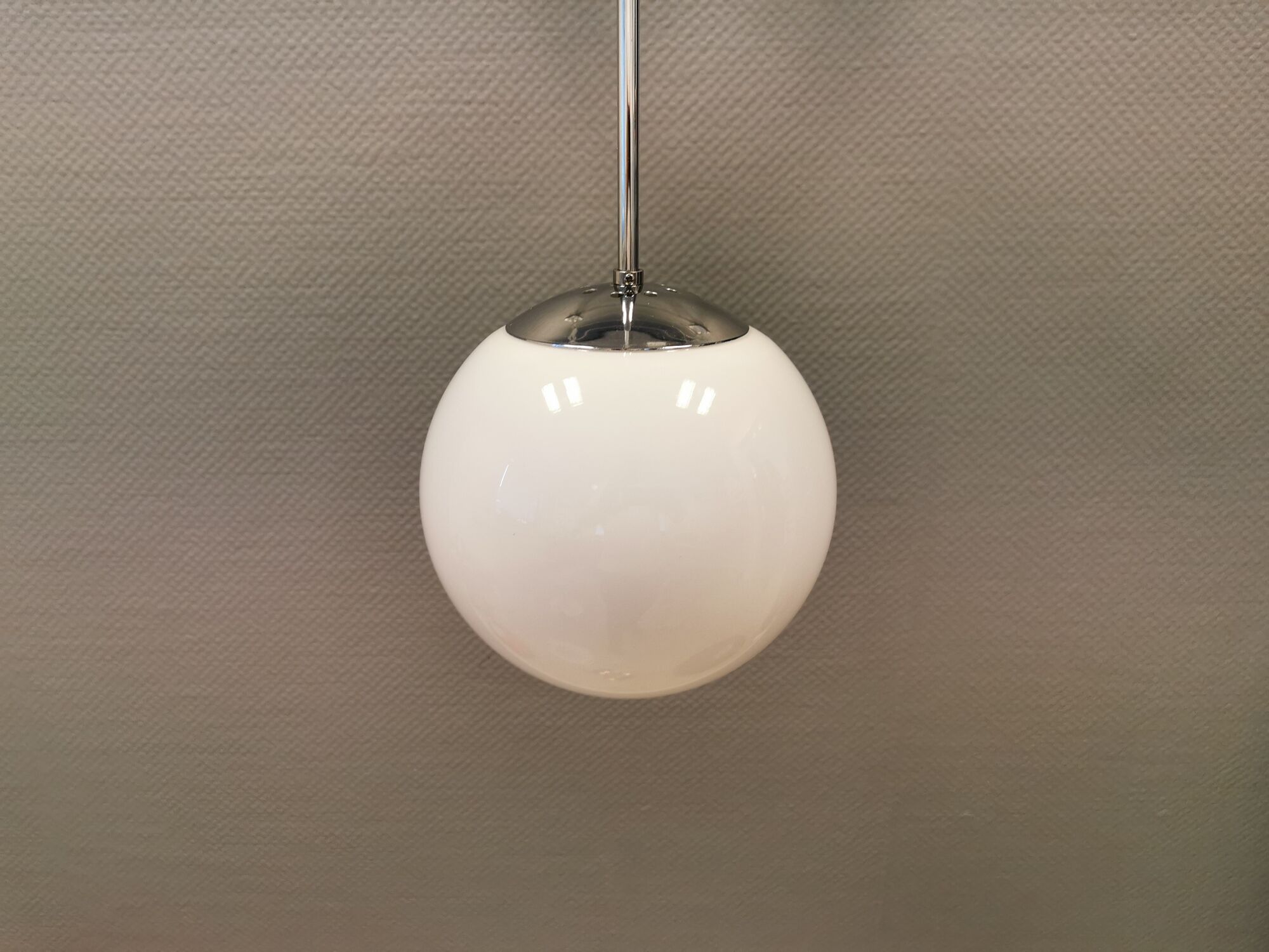White hanging lamp with metal suspension, made with ball round opal glass shade.