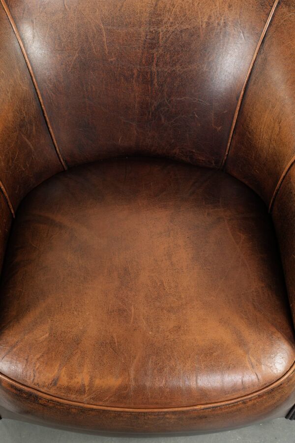 Fauteuil club en cuir de peau de mouton avec un coussin de siège fixe.