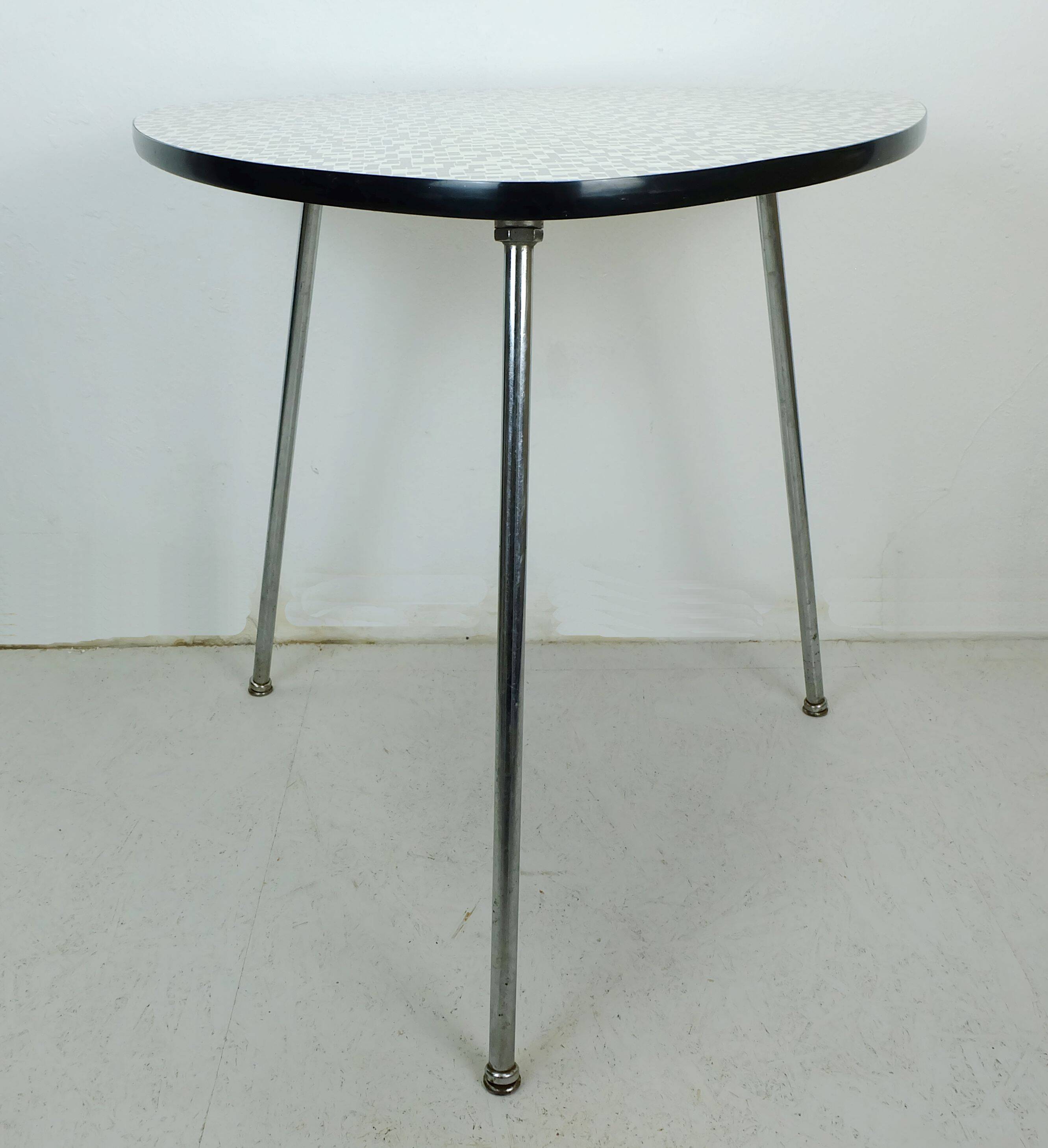 Table basse des années 1950 à trois pieds avec un plateau en formica et des pieds en chrome inclinés.