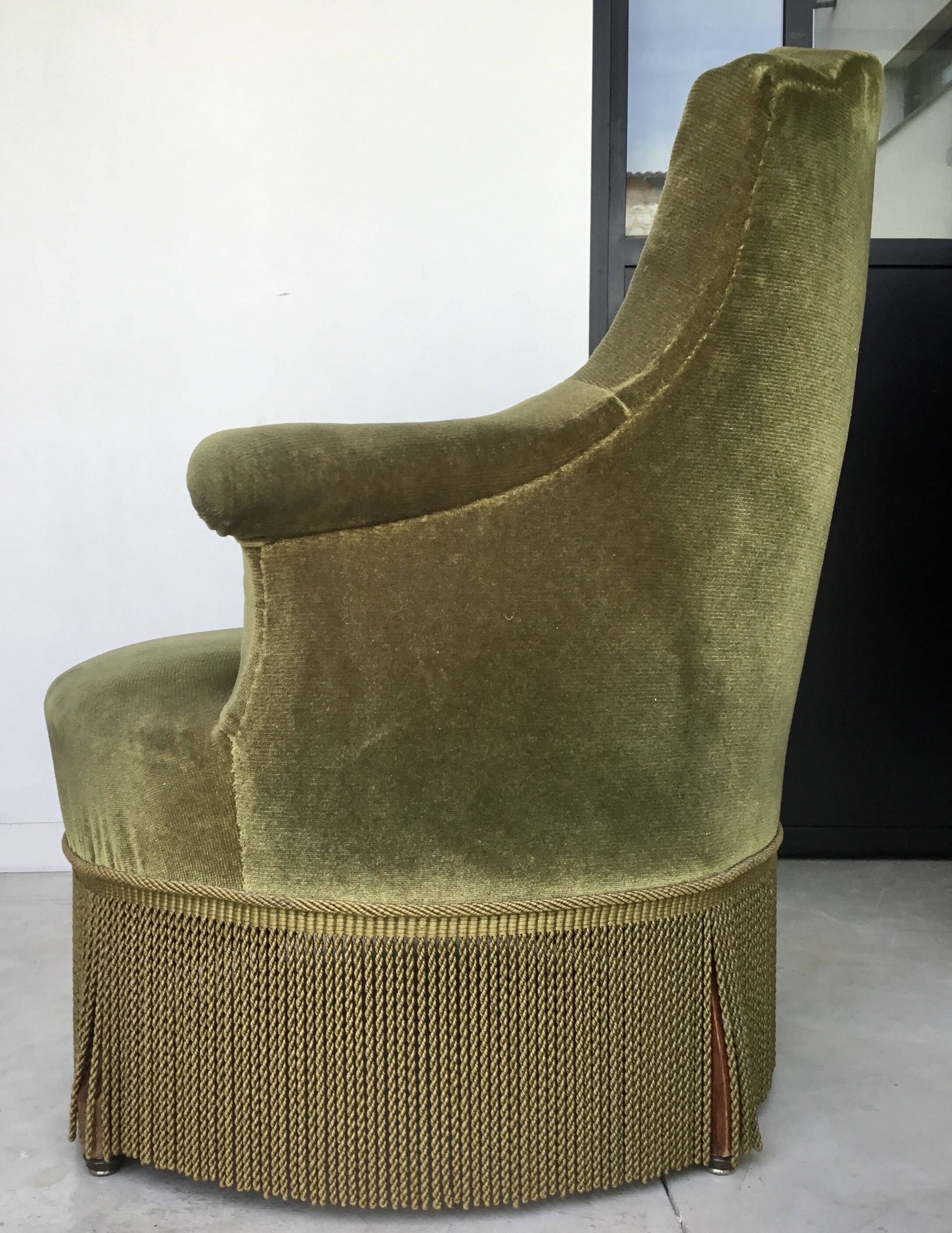 Olive green toad armchair with smooth velvet fringes.