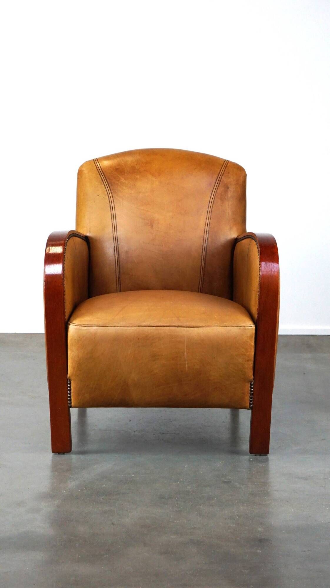 Luxurious cowhide Art Deco design armchair with wooden armrests and cognac-colored leather
