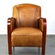 Luxurious cowhide Art Deco design armchair with wooden armrests and cognac-colored leather