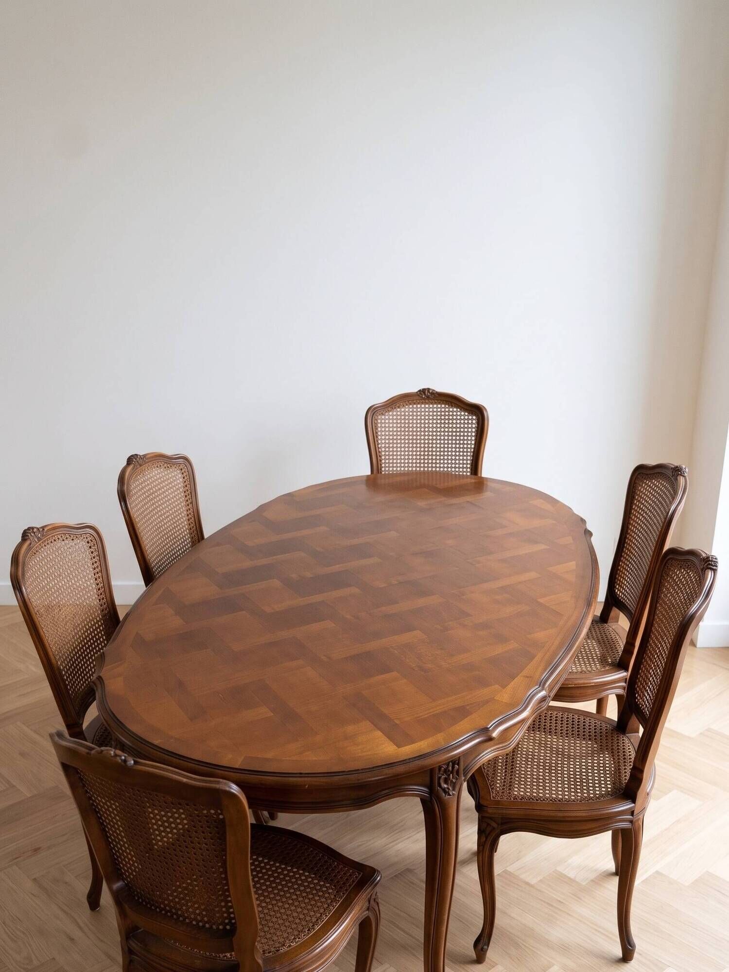 Oval dining table and 6 caned chairs in Louis XVI style made of wood.