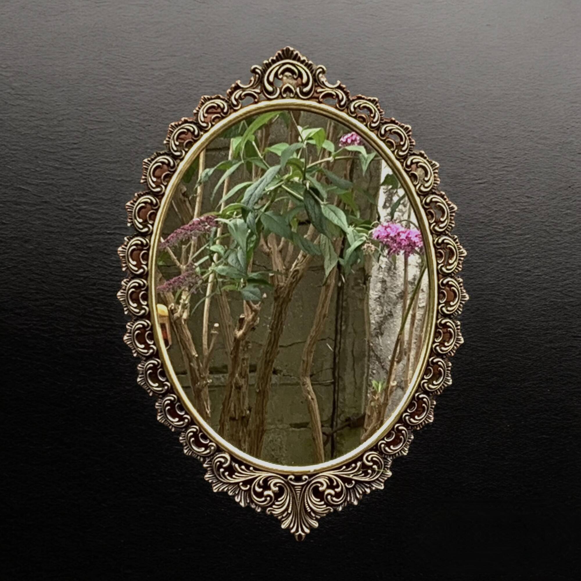 Old oval wall mirror in gilded brass