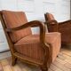 Pair of 1920s brown armchairs in carved wood and fabric, with caning detail.