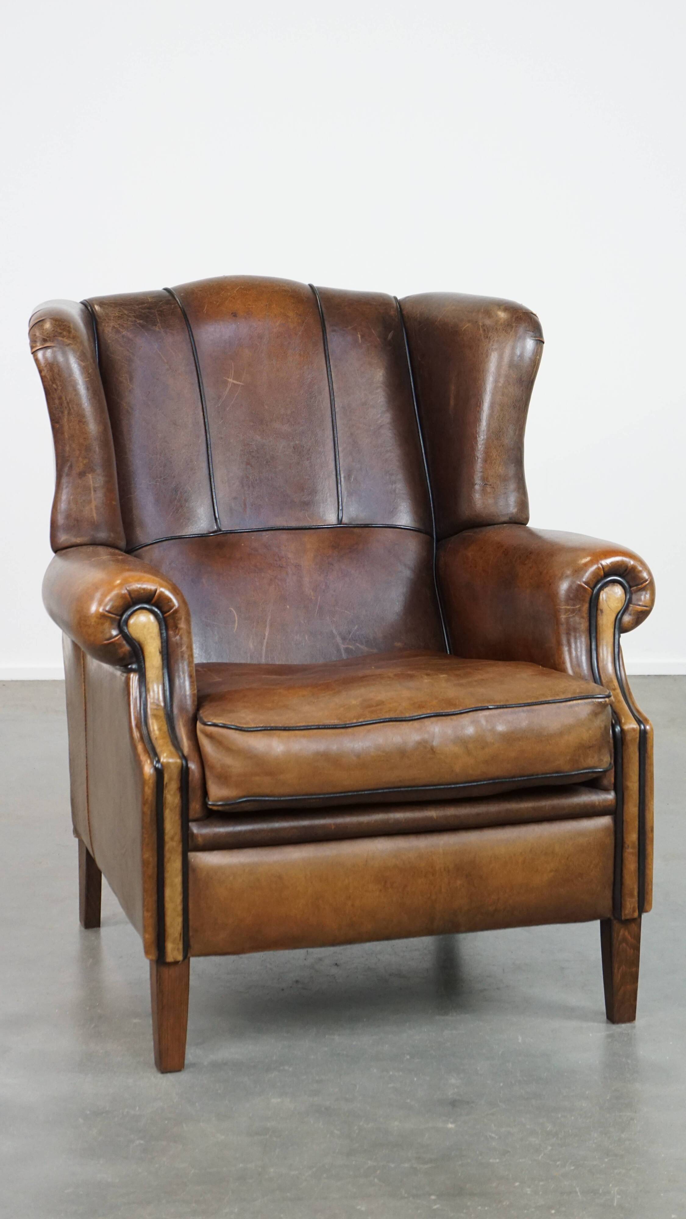 Vintage sheepskin wingback chair finished with black piping