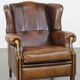 Vintage sheepskin wingback chair finished with black piping