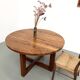 Modernist round table in solid elm, crossed legs.