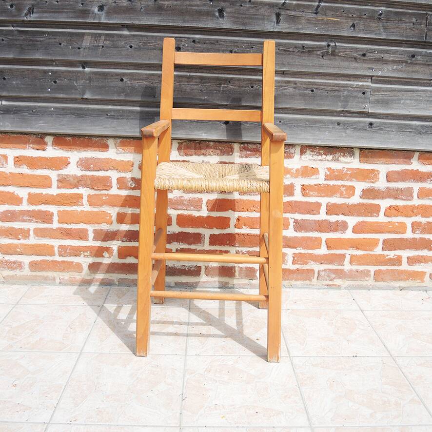 Old wooden high chair for children with straw.