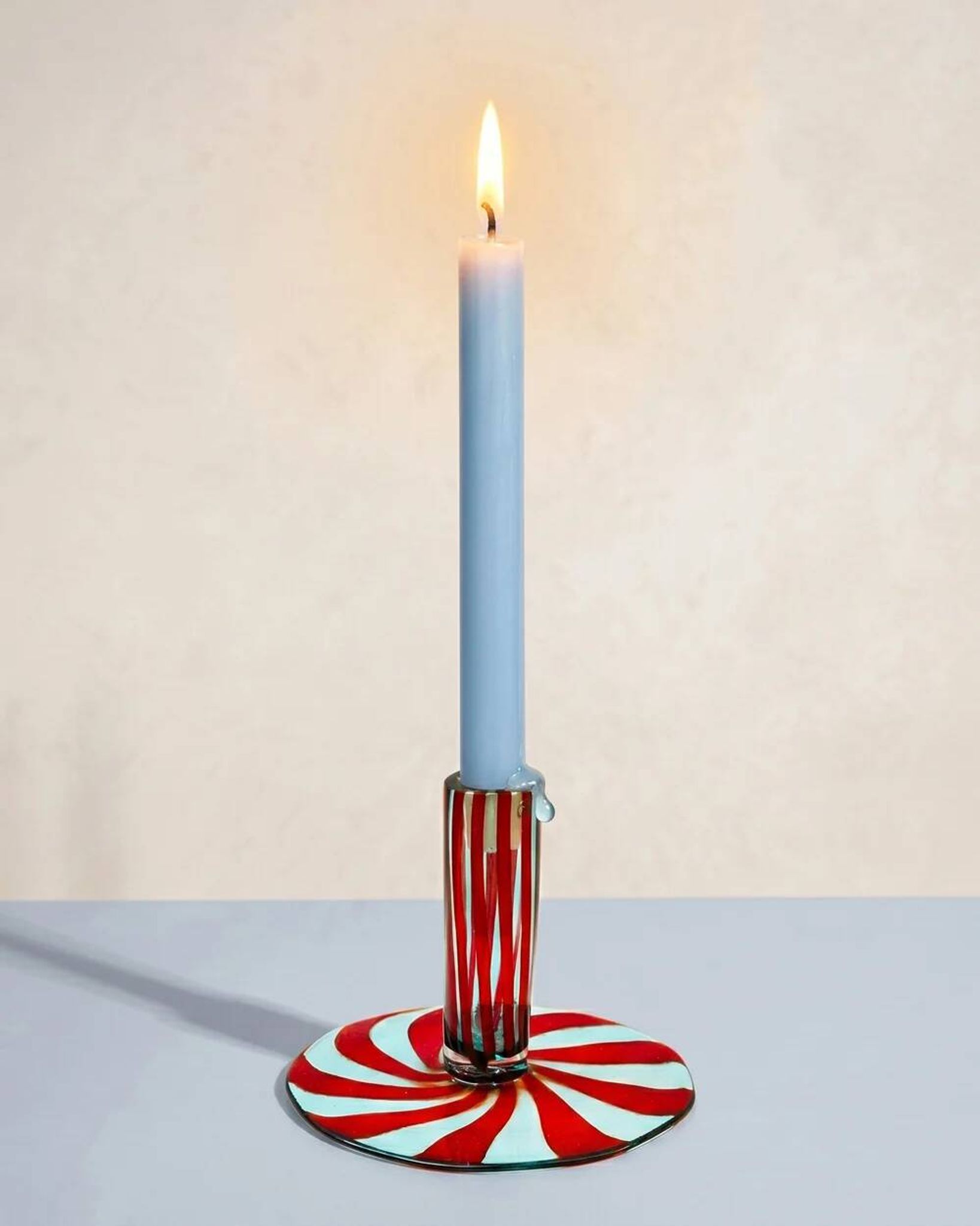 Murano glass candlestick with swirling red and blue ribbons.