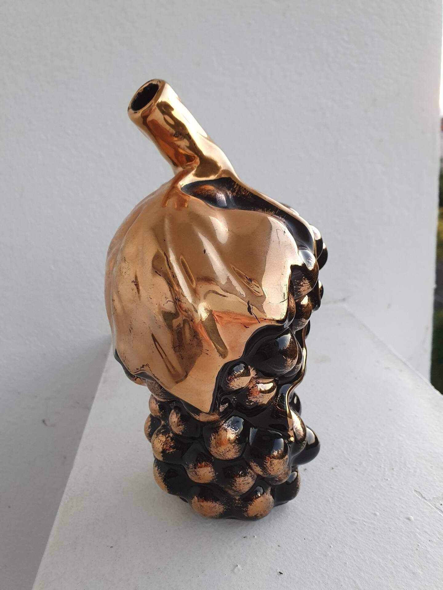 Beautiful black and gold ceramic bottle in the shape of a bunch of grapes.