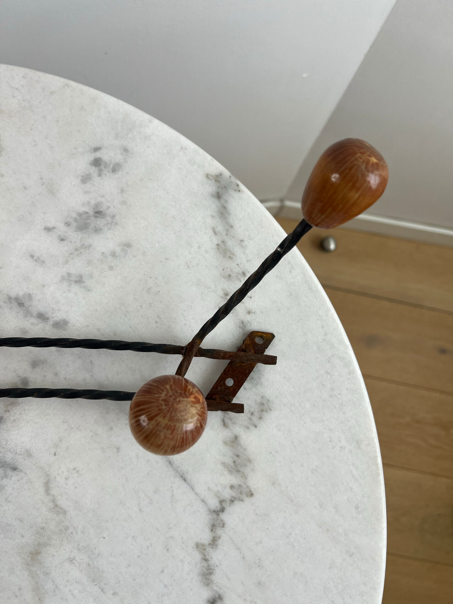 Wall-mounted coat rack in wrought iron with turned wooden knobs.