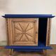 Small vintage upcycled side table in midnight blue and raw wood, with a rose-shaped door.