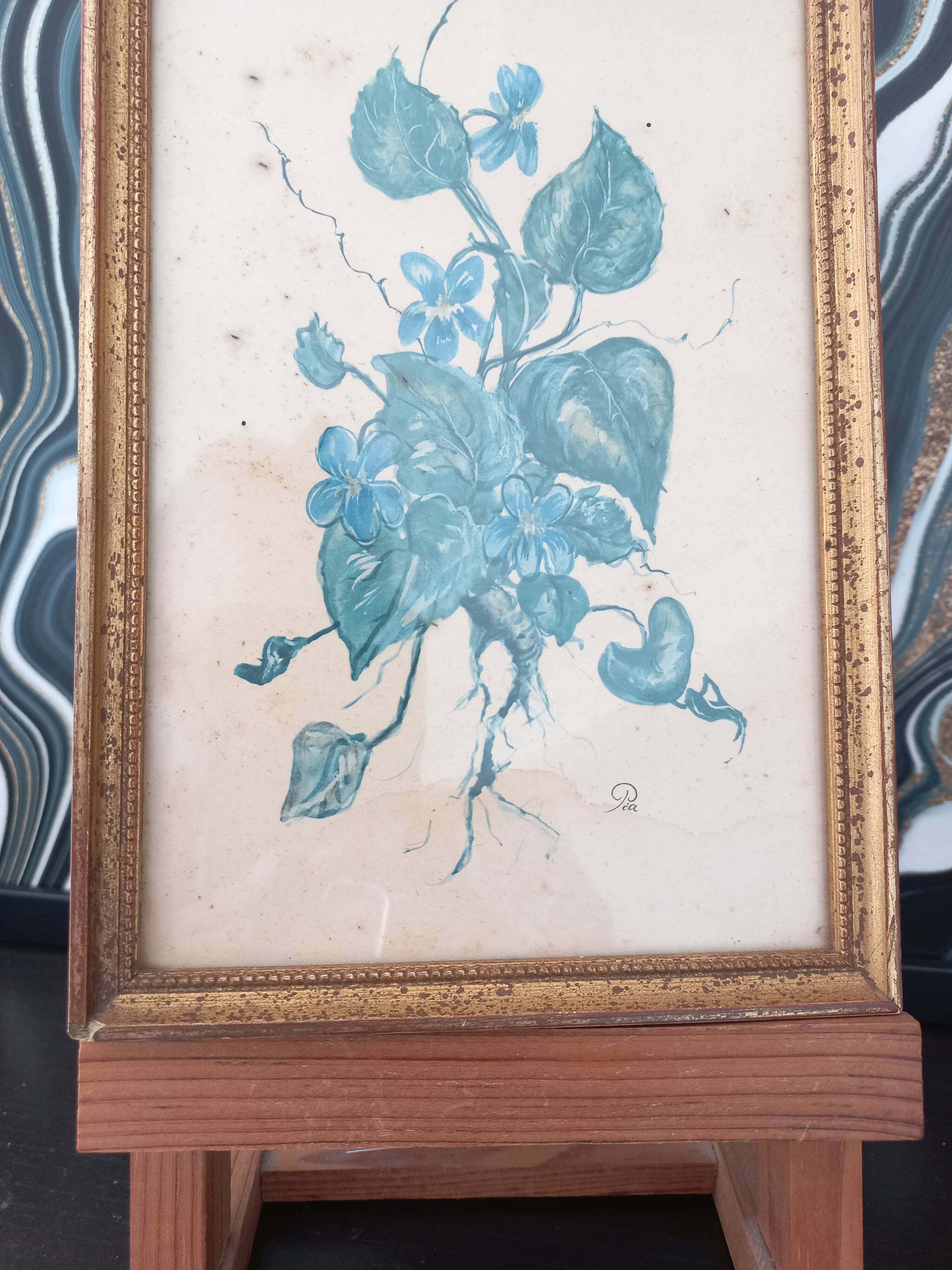 Decorative table with vintage blue flowers in a golden frame.